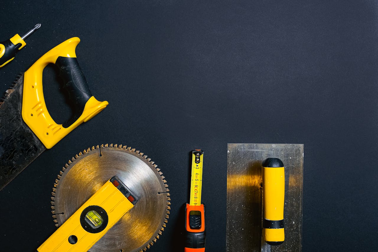 Hand tools arranged on a black surface, featuring saws, levels, and a tape measure.