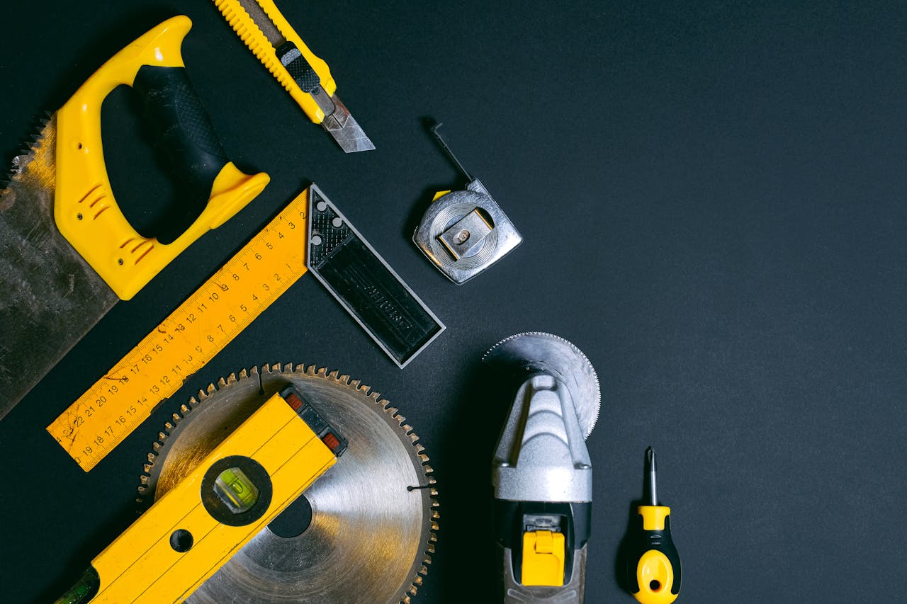 A collection of construction tools arranged on a dark surface offering copy space.